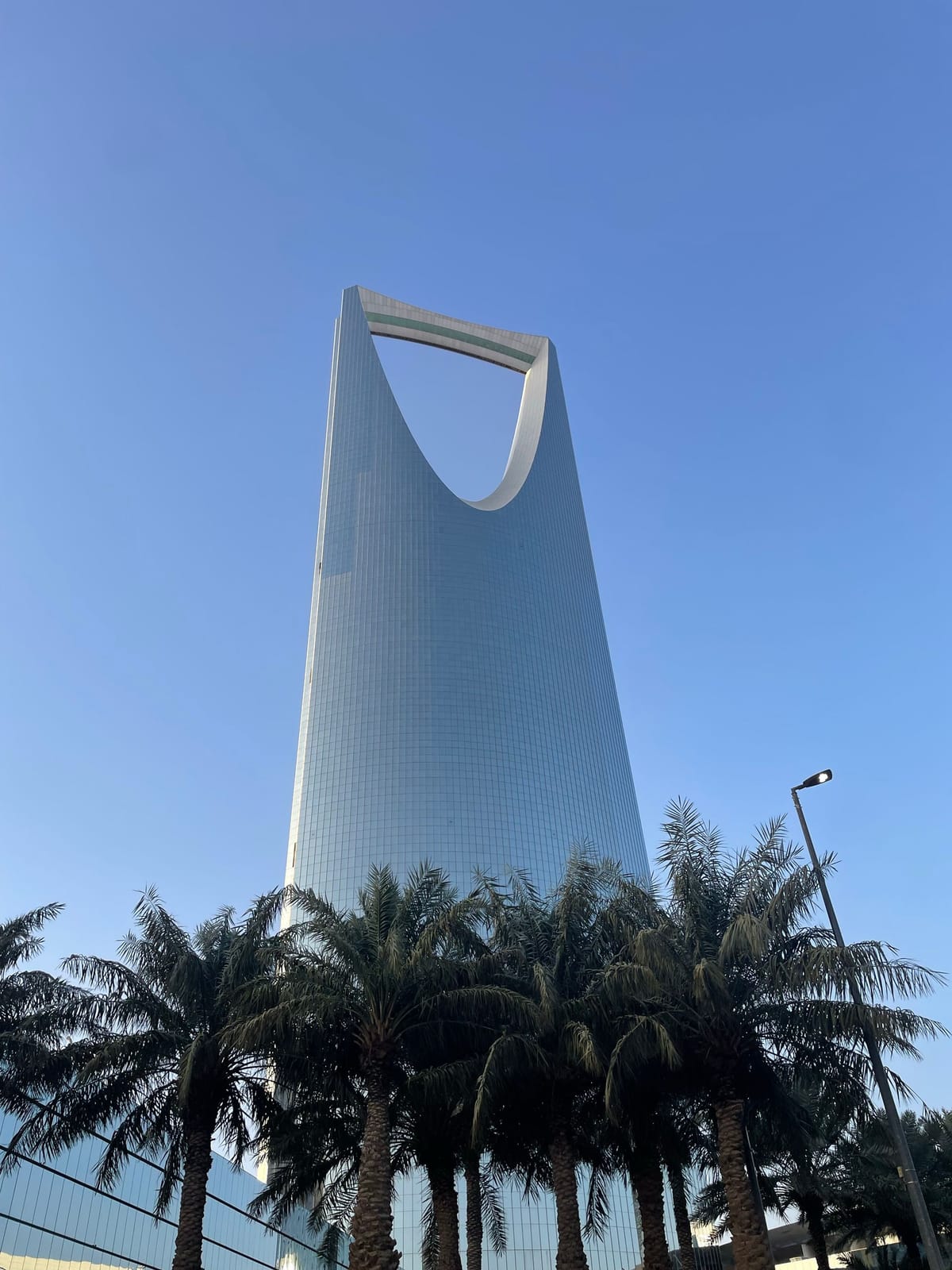 Kingdom Centre tower in Riyadh, Saudi Arabia, behind a row of palm trees