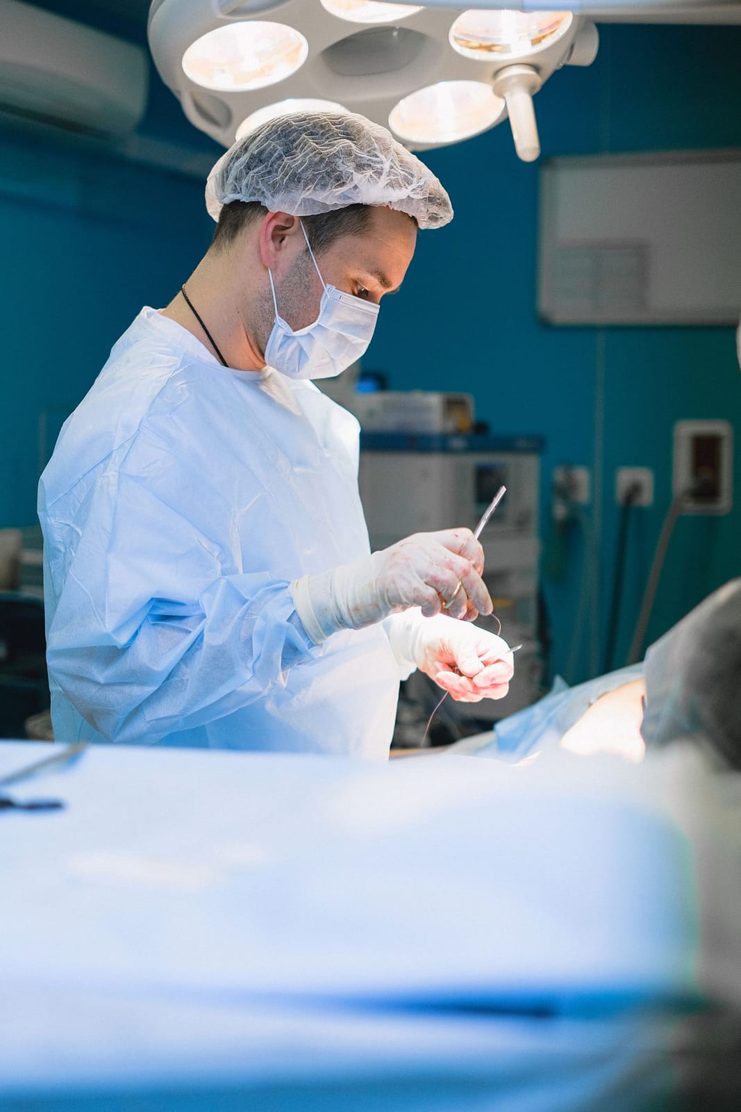 Surgeon in a disposable gown, bouffant cap and mask in an operating theatre